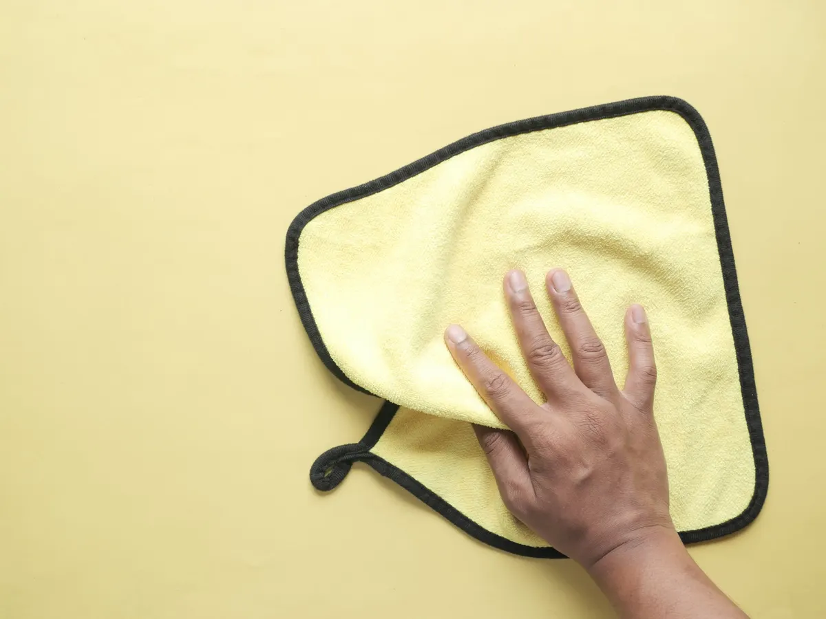 Hand holding a yellow microfiber cleaning cloth